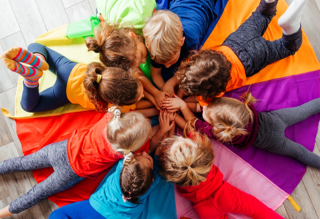 Children playing together on a colorful parachute during group activity